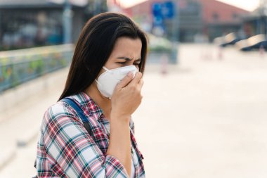 Çevre kirliliğini ve virüsü korumak için N95 maskesi takan Asyalı kadın. Covid-19 Coronavirus ve Hava kirliliği pm2.5 kavramı.