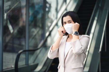 Çevre kirliliğini ve virüsü korumak için N95 maskesi takan Asyalı kadın. Covid-19 Coronavirus ve Hava kirliliği pm2.5 kavramı.