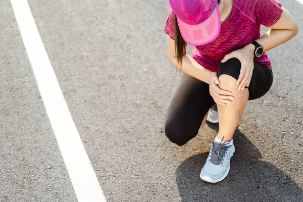 knee Injuries. sport woman with strong athletic legs holding knee with her hands in pain after suffering muscle injury during a running workout training on Running Track. Healthcare and sport concept.