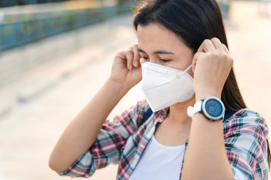 Çevre kirliliğini ve virüsü korumak için N95 maskesi takan Asyalı kadın. Covid-19 Coronavirus ve Hava kirliliği pm2.5 kavramı.
