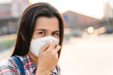 Çevre kirliliğini ve virüsü korumak için N95 maskesi takan Asyalı kadın. Covid-19 Coronavirus ve Hava kirliliği pm2.5 kavramı.