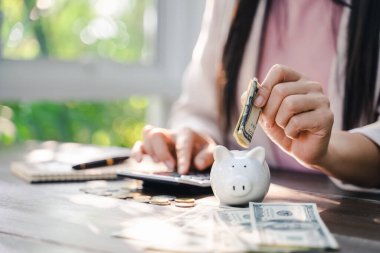 İş kadını eli, tasarruf için kumbaraya para koyuyor. Para ve finansal konsept tasarrufu