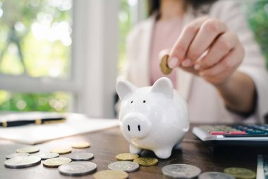 İş kadını eli, tasarruf için kumbaraya para koyuyor. Para ve finansal konsept tasarrufu