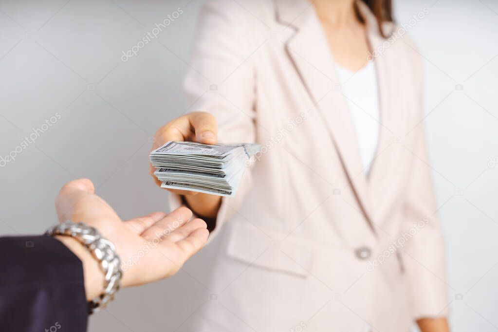 Businesswoman giving money to her partner while making contract - bribery and corruption concepts