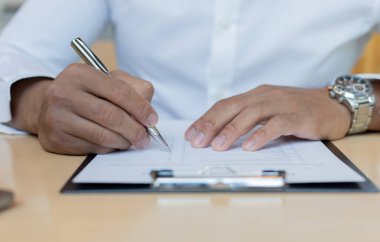 Bir finans işadamı, genç bir adam finansal verileri bilgisayar ve hesap makinesi kullanarak analiz eder ve verileri bir grafikte özetleyip başkana sunar..