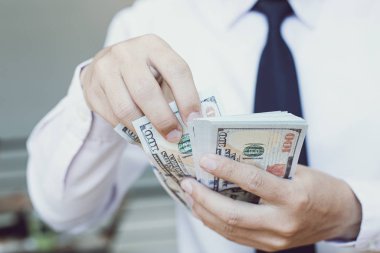 Genç adam elinde bir dolar saydı, mali hesap yönetimi ve ödeme veya tasarruf kavramı.