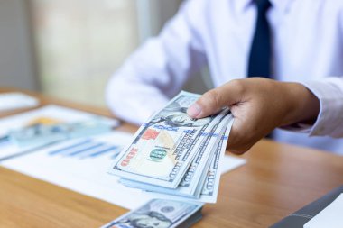 Genç adam elinde bir dolar saydı, mali hesap yönetimi ve ödeme veya tasarruf kavramı.