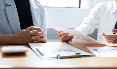Şirketin gelir grafiğiyle ilgili iş adamları, yöneticiler ve muhasebecilerden oluşan bir ekiple ofiste dizüstü bilgisayarlar, hesap makineleri ve finans konseptiyle bir araya gelmek