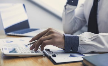 İşadamları şirketin vergi ve gelirlerini, mali ve muhasebe bankacılığı kavramlarını hesaplamak için hesap makineleri kullanıyorlar.