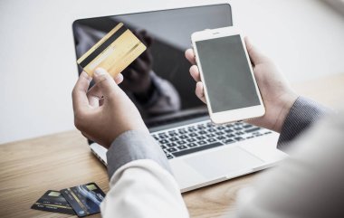 Men Hands kredi kartı tutuyor ve dizüstü bilgisayar kullanıyor. Çevrimiçi alışveriş kavramı