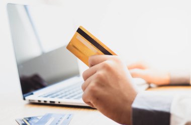 Men Hands kredi kartı tutuyor ve dizüstü bilgisayar kullanıyor. Çevrimiçi alışveriş kavramı