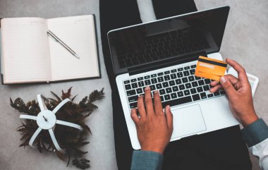 Men Hands kredi kartı tutuyor ve dizüstü bilgisayar kullanıyor. Çevrimiçi alışveriş kavramı