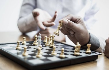 İş adamları ve kadınlar, risk azaltmak ve başarı, yönetim veya liderlik kavramına ulaşmak için satranç stratejilerini analiz ederler..