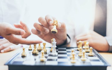İş adamları ve kadınlar, risk azaltmak ve başarı, yönetim veya liderlik kavramına ulaşmak için satranç stratejilerini analiz ederler..