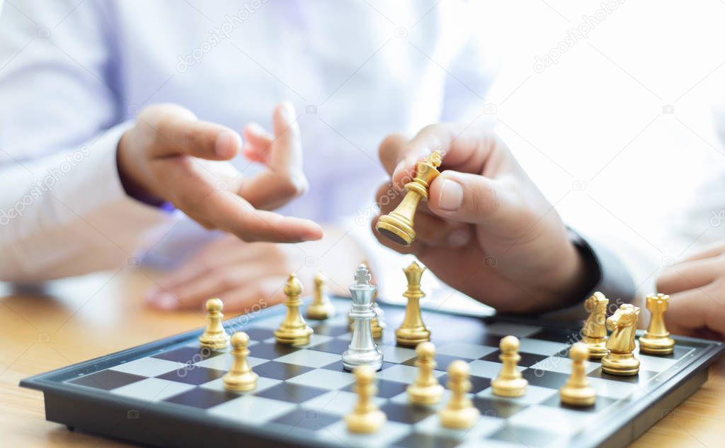 Business men and women analyze chess playing strategies to reduce risks and achieve success, Management or leadership concept.