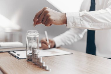 Bir bardakta bozuk para bulundurun, İşadamları gelir hesaplayarak finansal bir plan hazırlar - istikrarlı iş büyüme fikirleri için harcamalar, para tasarrufu kavramı