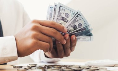 İş adamının eli masadaki dolar banknotlarını sayıyor..