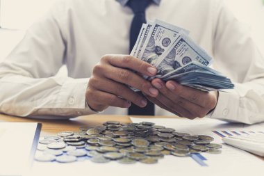 İş adamının eli masadaki dolar banknotlarını sayıyor..