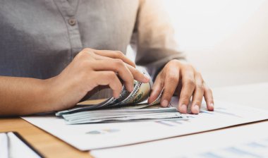 İş adamının eli masadaki dolar banknotlarını sayıyor..