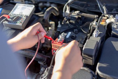 Otomotiv teknisyeni, ammetre, araba onarım hizmeti konseptini kullanarak motorun durumunu inceledi..