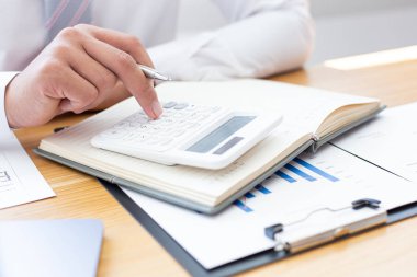 İşadamları emlak yatırımlarının maliyetini hesaplamak için hesap makineleri kullanırlar ve şirket Business Financ Concept ile hisse paylaşmak isteyen müşterilere teklif sunmaya hazırlanırlar.