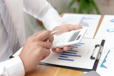 İşadamları emlak yatırımlarının maliyetini hesaplamak için hesap makineleri kullanırlar ve şirket Business Financ Concept ile hisse paylaşmak isteyen müşterilere teklif sunmaya hazırlanırlar.