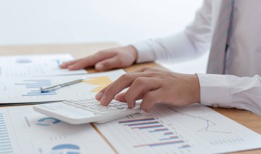 İşadamları emlak yatırımlarının maliyetini hesaplamak için hesap makineleri kullanırlar ve şirket Business Financ Concept ile hisse paylaşmak isteyen müşterilere teklif sunmaya hazırlanırlar.