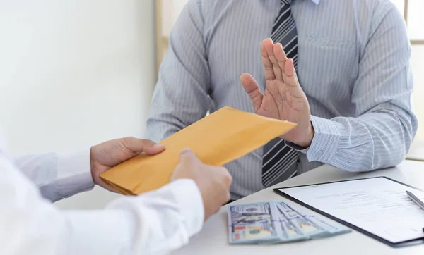 Businessman refusing to receive the money in a brown envelope to sign a business contract ,Anti bribery and corruption concept