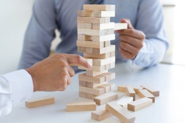 İş adamları birlikte ahşap oyunlar oynar, bir işletmenin ortalama yatırım değerini böler ve riskleri ortaklaşa yönetir, Alternatif risk planı ve iş stratejisi.