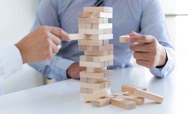 İş adamları birlikte ahşap oyunlar oynar, bir işletmenin ortalama yatırım değerini böler ve riskleri ortaklaşa yönetir, Alternatif risk planı ve iş stratejisi.