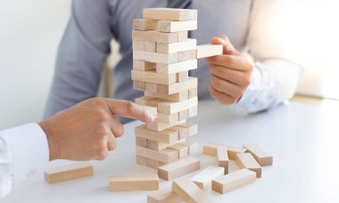 İş adamları birlikte ahşap oyunlar oynar, bir işletmenin ortalama yatırım değerini böler ve riskleri ortaklaşa yönetir, Alternatif risk planı ve iş stratejisi.