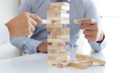 İş adamları birlikte ahşap oyunlar oynar, bir işletmenin ortalama yatırım değerini böler ve riskleri ortaklaşa yönetir, Alternatif risk planı ve iş stratejisi.