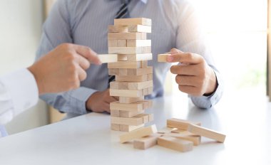 İş adamları birlikte ahşap oyunlar oynar, bir işletmenin ortalama yatırım değerini böler ve riskleri ortaklaşa yönetir, Alternatif risk planı ve iş stratejisi.