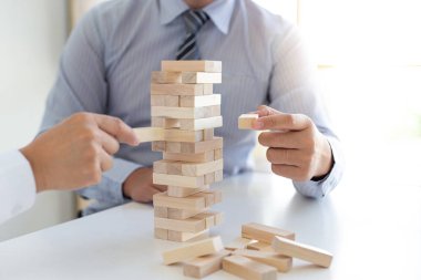 İş adamları birlikte ahşap oyunlar oynar, bir işletmenin ortalama yatırım değerini böler ve riskleri ortaklaşa yönetir, Alternatif risk planı ve iş stratejisi.