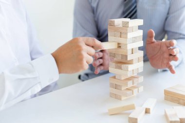 İş adamları birlikte ahşap oyunlar oynar, bir işletmenin ortalama yatırım değerini böler ve riskleri ortaklaşa yönetir, Alternatif risk planı ve iş stratejisi.