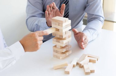 İş adamları birlikte ahşap oyunlar oynar, bir işletmenin ortalama yatırım değerini böler ve riskleri ortaklaşa yönetir, Alternatif risk planı ve iş stratejisi.