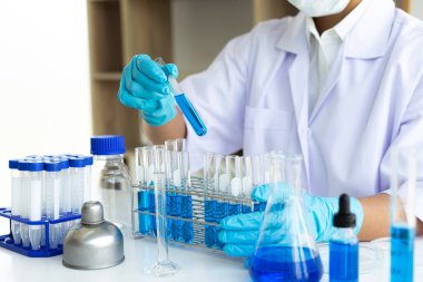 Bilim insanları kimyasal bileşimin ve biyolojik kütlesinin bilimsel bir laboratuvarda, bilim adamlarında ve laboratuar konseptinde tespit edilmesine hazırlanmak için mavi kimyasal test tüpleri taşıyorlar..