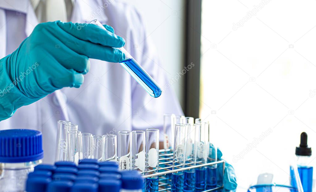 Scientists are carrying blue chemical test tubes to prepare for the determination of chemical composition and biological mass in a scientific laboratory, Scientists and research in the lab Concept.