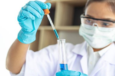 Bilim insanları kimyasal bileşimin ve biyolojik kütlesinin bilimsel bir laboratuvarda, bilim adamlarında ve laboratuar konseptinde tespit edilmesine hazırlanmak için mavi kimyasal test tüpleri taşıyorlar..