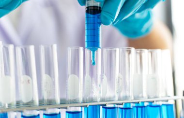 Bilim insanları kimyasal bileşimin ve biyolojik kütlesinin bilimsel bir laboratuvarda, bilim adamlarında ve laboratuar konseptinde tespit edilmesine hazırlanmak için mavi kimyasal test tüpleri taşıyorlar..
