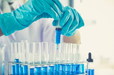 Bilim insanları kimyasal bileşimin ve biyolojik kütlesinin bilimsel bir laboratuvarda, bilim adamlarında ve laboratuar konseptinde tespit edilmesine hazırlanmak için mavi kimyasal test tüpleri taşıyorlar..
