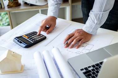 Mühendis bina yapısını tasarladı ve mimarın odasında çalışıyor dizüstü bilgisayarlar, kalemler, çizimler ve kalıplı örnek evler tasarlamak için ekipmanlar var. 