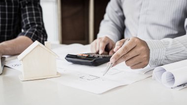 Mühendisler ya da mimarlar, mimari yapıyı tasarlamak için bir ekiple buluşacak. Çalışma alanı, teknolojik yapı ve inşaat alanındaki planlar ve model binalarla birlikte..