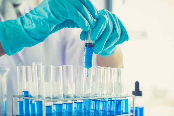 Bilim insanları kimyasal bileşimin ve biyolojik kütlesinin bilimsel bir laboratuvarda, bilim adamlarında ve laboratuar konseptinde tespit edilmesine hazırlanmak için mavi kimyasal test tüpleri taşıyorlar..
