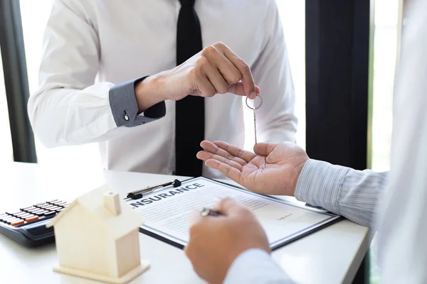 The sales manager or real estate sales representative handed the keys to the customer after signing the contract, signing the lease or buying a house with home loan and home insurance offers, Finance or accounting and insurance sales Concept