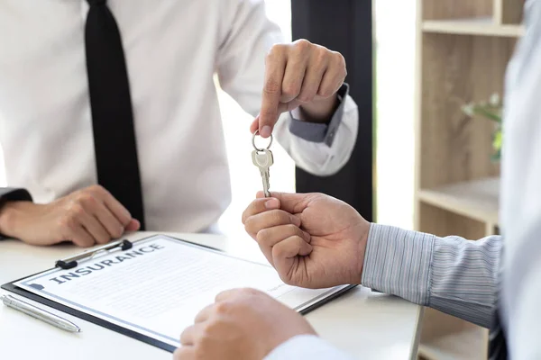 The sales manager or real estate sales representative handed the keys to the customer after signing the contract, signing the lease or buying a house with home loan and home insurance offers, Finance or accounting and insurance sales Concept