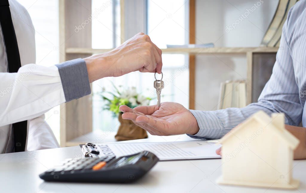 The sales manager or real estate sales representative handed the keys to the customer after signing the contract, signing the lease or buying a house with home loan and home insurance offers, Finance or accounting and insurance sales Concept