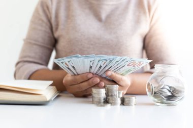 İş kadınlarının elinde bir banknot, bir dolar para var. Ekonomik kriz, tasarruf, finans ve muhasebe kavramı için günlük gelir ve harcamaları kaydetmeye hazır olun.