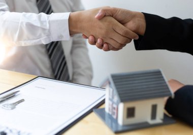 Mülk yöneticisi, evi sigorta, el sıkışma, başarı ve tebrik konseptiyle satın alan müşterileri tebrik ediyor..