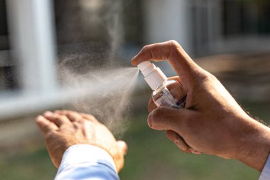 Genç erkekler CORONA veya grip COVID-19, CORONA veya COVID-19 hastalığının yayılmasını önlemek ve kontrol etmek için% 70 alkol spreyi kullanırlar..